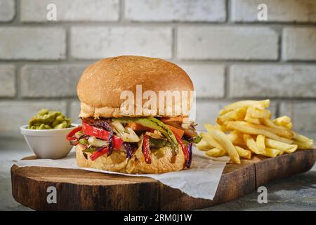 Schließen Sie köstliche frische Burger und Pommes Frites auf Holzbrett. Und Backsteinhintergrund. Isoliertes Bild eines schönen Hamburger Stockfoto