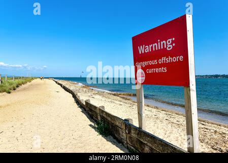 Ein großes rotes Schild am Strand warnt die Öffentlichkeit vor „gefährlichen Offshore-Strömungen“ im Lepe Country Park an einem Sommertag in Hampshire England Stockfoto