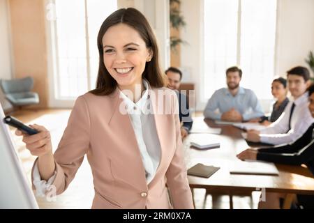 Smiling Caucasian female coach make presentation at meeting Stock Photo