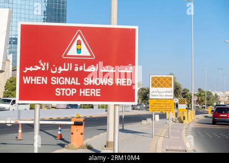 Zweisprachiges Straßenschild auf Englisch und Arabisch - wenn das Signal rot anzeigt, halten Sie hier an. Straßenschild in Bahrain, Naher Osten Stockfoto