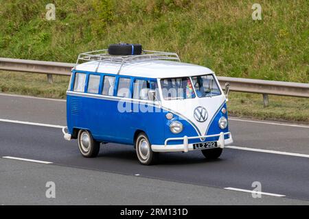 1975 70er Jahre Blauer weißer Benzinmotor 1600 ccm VW VW Typ 2 Camper Van Split Screen 11-Fenster-Minibus, der auf der Autobahn M6 in Greater Manchester, Großbritannien, mit hoher Geschwindigkeit fährt Stockfoto