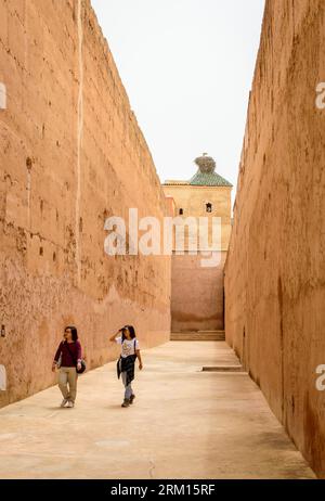 Marrakesch, Marokko, 8. April 2023. Touristen laufen in der Nähe der hohen alten Mauern im Marrakesch Badi Palast. Stockfoto