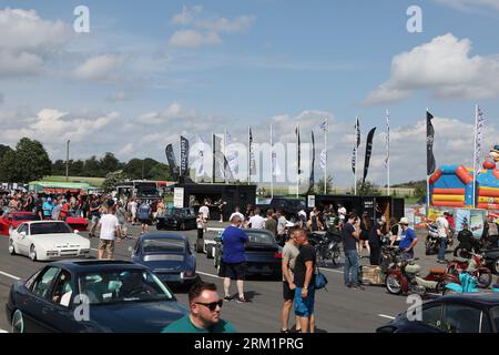 Schleiz, Deutschland. 26. August 2023. Bei der Eröffnung der Motorwelt „Schleizer Dreieck“ laufen die Besucher durch die Ausstellungsfläche. Der Schleizer Dreieck ist Deutschlands älteste Strassenbahn und auch heute noch Austragungsort von Motorsportrennen. Das Museum ist der hundertjährigen Geschichte der Rennstrecke gewidmet. Quelle: Bodo Schackow/dpa/Alamy Live News Stockfoto