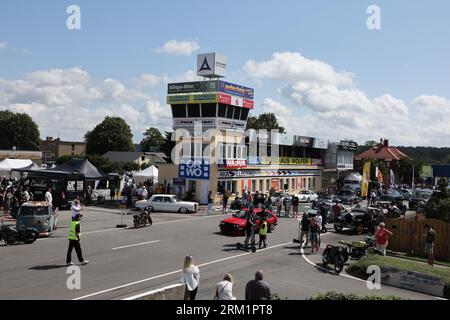 Schleiz, Deutschland. 26. August 2023. Bei der Eröffnung der Motorwelt „Schleizer Dreieck“ laufen die Besucher durch die Ausstellungsfläche. Der Schleizer Dreieck ist Deutschlands älteste Strassenbahn und auch heute noch Austragungsort von Motorsportrennen. Das Museum ist der hundertjährigen Geschichte der Rennstrecke gewidmet. Quelle: Bodo Schackow/dpa/Alamy Live News Stockfoto