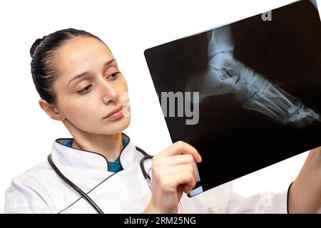 Junge Ärztin, die eine Röntgenplatte in der Hand auf weißem Hintergrund hält Stockfoto