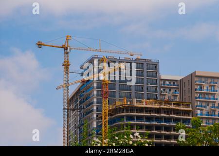 Zwei gelbe Turmdrehkrane und unvollendete Gebäudekonstruktion Stockfoto