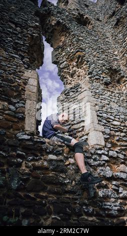 Ein Mann sitzt auf dem Fenster der Ruine der Church of St James Church in der Nähe von Kings Lynn in Norfolk, England Stockfoto