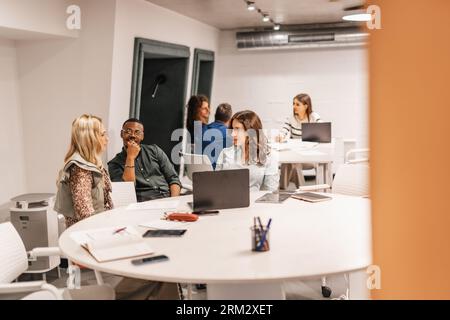 Multirassische, generationenübergreifende Kollegen lernen gemeinsam im modernen Klassenzimmer, diskutieren Arbeit, teilen Wissen und Ideen. Stockfoto