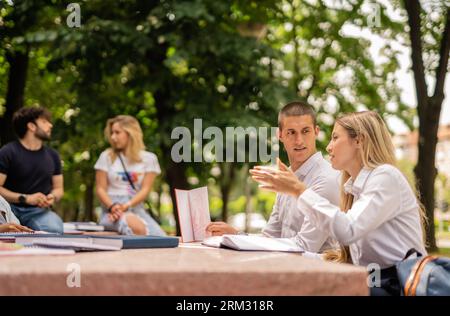 Motivierte Studenten versammelten sich am Tisch, diskutierten das Thema der Universität und arbeiteten gemeinsam an einem Projekt Stockfoto