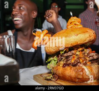 Bildnummer: 60084456  Datum: 09.07.2013  Copyright: imago/Xinhua (130709) -- NAIROBI, July 9, 2013 (Xinhua) -- Photo taken on July 9, 2013 shows a big burger during a burger challenge at Brew Bistro in Nairobi, capital of Kenya. Four contestants had one hour to finish a 5kg burger with beef, two huge burger buns and 40 toppings. Sauti Sol team won the burger challenge. (Xinhua/Meng Chenguang) KENYA-NAIROBI-BURGER CHALLENGE PUBLICATIONxNOTxINxCHN Gesellschaft Kultur Burgerwettessen Food Hamburger Burger Wettessen xdp x0x 2013 quadrat premiumd      60084456 Date 09 07 2013 Copyright Imago XINHUA Stock Photo