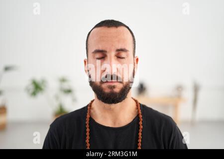 Close-up kaukasischer Mann mit Bart, der Yoga-Meditation macht. Männliche Konzentrationserscheinungen mittleren Alters geschlossen Stockfoto