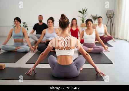 Gruppe verschiedene Fitness junge Menschen üben Yoga-Übungen in Innenräumen. Konzentriertes Meditieren. Stockfoto