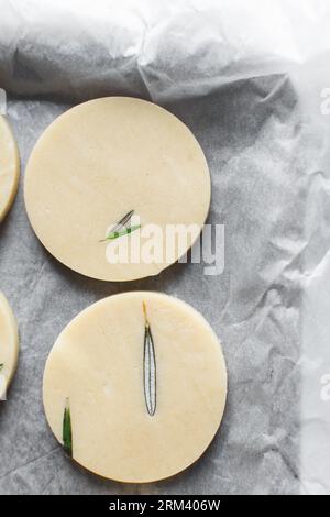 Draufsicht auf ausgeschnittenen rohen Rosmarin-Zucker-Keksenteig, Rosmarin-Keksenteig, der gerade gebacken wird, Prozess der Herstellung von Rosmarin-Zucker-Keksen Stockfoto