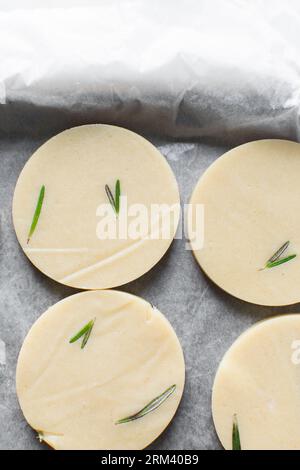 Draufsicht auf ausgeschnittenen rohen Rosmarin-Zucker-Keksenteig, Rosmarin-Keksenteig, der gerade gebacken wird, Prozess der Herstellung von Rosmarin-Zucker-Keksen Stockfoto
