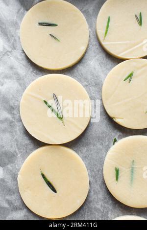 Draufsicht auf ausgeschnittenen rohen Rosmarin-Zucker-Keksenteig, Rosmarin-Keksenteig, der gerade gebacken wird, Prozess der Herstellung von Rosmarin-Zucker-Keksen Stockfoto