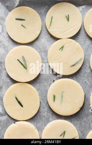 Draufsicht auf ausgeschnittenen rohen Rosmarin-Zucker-Keksenteig, Rosmarin-Keksenteig, der gerade gebacken wird, Prozess der Herstellung von Rosmarin-Zucker-Keksen Stockfoto