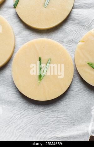 Draufsicht auf ausgeschnittenen rohen Rosmarin-Zucker-Keksenteig, Rosmarin-Keksenteig, der gerade gebacken wird, Prozess der Herstellung von Rosmarin-Zucker-Keksen Stockfoto