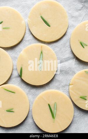 Draufsicht auf ausgeschnittenen rohen Rosmarin-Zucker-Keksenteig, Rosmarin-Keksenteig, der gerade gebacken wird, Prozess der Herstellung von Rosmarin-Zucker-Keksen Stockfoto
