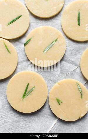 Draufsicht auf ausgeschnittenen rohen Rosmarin-Zucker-Keksenteig, Rosmarin-Keksenteig, der gerade gebacken wird, Prozess der Herstellung von Rosmarin-Zucker-Keksen Stockfoto
