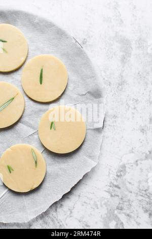 Draufsicht auf ausgeschnittenen rohen Rosmarin-Zucker-Keksenteig, Rosmarin-Keksenteig, der gerade gebacken wird, Prozess der Herstellung von Rosmarin-Zucker-Keksen Stockfoto