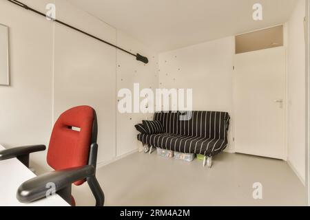 Ein Wohnzimmer mit schwarz-weiß gestreifter Couch, rotem Stuhl und Tapeten an den Wänden Stockfoto