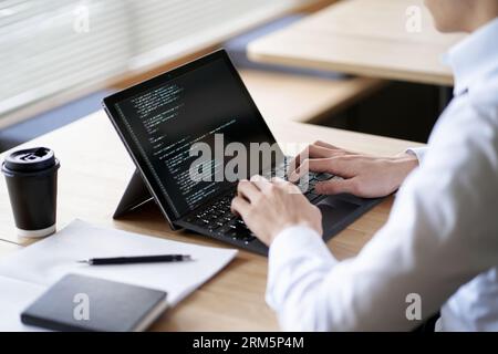 Asiatischer Programmierer, der Code auf einem Laptop schreibt Stockfoto