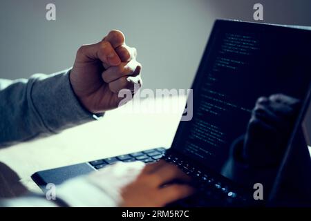 Ein männlicher Hacker, der erfolgreich einen Mut macht Stockfoto