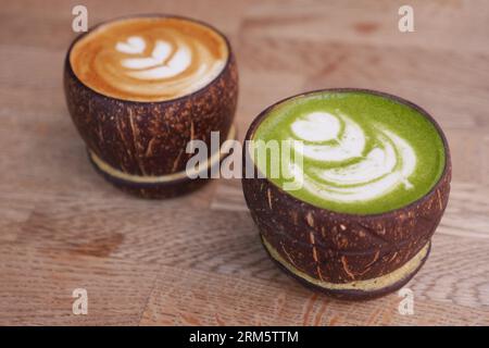 Latte und Matcha Latte in einer Kokosnussschale auf dem Tisch Stockfoto