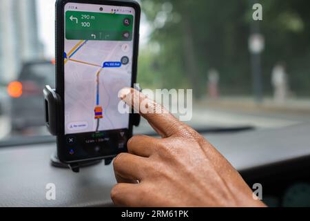Männliche Hand und Smartphone im Auto. Der Mann fährt ein Auto mit GPS-Navigationssystem auf seinem Telefon, während er fährt, zum Ziel. Transport, Technologie. Mobi Stockfoto