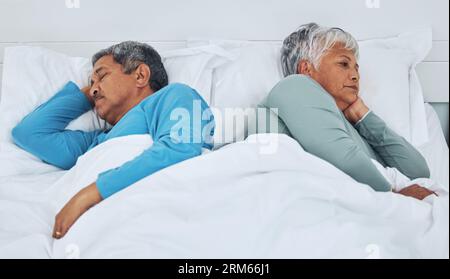 Schlafen, Kämpfen und ein älteres Paar in einem Bett mit Schlaflosigkeit in einer Ehe. Konflikt, müder und älterer Mann und Frau im Schlafzimmer für Stockfoto