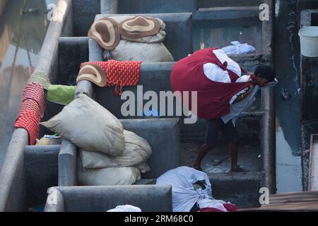 (131218) -- MUMBAI, 18. Dez. 2013 (Xinhua) -- Ein Portier trägt die gewaschene Kleidung im Dhobi Ghat in Mumbai, Indien, 18. Dez. 2013. Das Dhobi Ghat mit mehr als 150 Jahren Geschichte befindet sich im Stadtzentrum von Mumbai. Es wird als der größte Freiluft-Waschsalon der Welt bezeichnet. Die Waschmaschinen, lokal als Dhobis bekannt, arbeiten im Freien für Besitzer der Waschteiche, um die Kleidung von Mumbais Hotels und Krankenhäusern zu waschen. Sie leben mit ihrer Familie im Dhobi Ghat und verdienen Hunderte indische Rupien pro Tag. (Xinhua/Zheng Huansong) INDIA-MUMBAI-DHOBI GHAT PUBLICATIONxNOTxINxCHN Mumbai Stockfoto