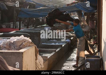 (131218) -- MUMBAI, Dec. 18, 2013 (Xinhua) -- A worker throws the clothes to the pond at the Dhobi Ghat in Mumbai, India, Dec. 18, 2013. The Dhobi Ghat, with more than 150 years of history, locates in the city centre of Mumbai. It is recorded as the world s largest open-air laundromat. The washers, locally known as Dhobis, work in the open air for owners of the washing ponds to wash the clothes from Mumbai s hotels and hospitals. They live with their family in the Dhobi Ghat, earning hundreds of Indian Rupees per day. (Xinhua/Zheng Huansong) INDIA-MUMBAI-DHOBI GHAT PUBLICATIONxNOTxINxCHN   Mum Stock Photo