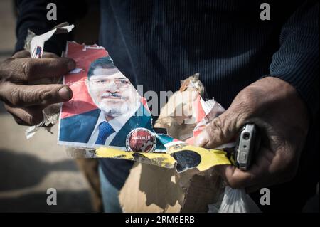 (140108) -- KAIRO, 8. Januar 2014 (Xinhua) -- ein Gegner zerreißt ein Porträt des gestürzten Präsidenten Mohamed Mursi vor der Polizeiakademie, wo die zweite Verhandlung des gestürzten ägyptischen Präsidenten Mohamed Mursi stattfinden sollte, in Kairo, Ägypten, 8. Januar 2014. Das Kairoer Strafgericht vertagte am Mittwoch den Prozess gegen den vertriebenen Präsidenten Mohamed Mursi wegen der Anstiftung zum Töten von Demonstranten auf den 1. Februar, da das schlechte Wetter seinen Transport zum Gericht verhinderte, berichtete das staatliche Fernsehen. (Xinhua/Pan Chaoyue)(hy) ÄGYPTEN-POLITIK-MURSI-PROZESS-VERTAGT PUBLICATIONxNOTxINxCHN Kairo 8. Januar 2014 XINHUA auf Opponation Stockfoto