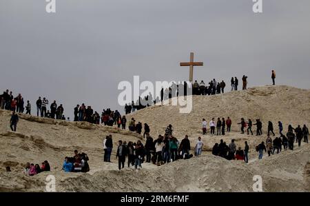 (140111) -- AMMAN, Jan. 11, 2014 (Xinhua) -- Christian pilgrims from around the world climb a small mountain near the Jordan River baptism site to take photos with a giant wooden cross, Jordan Valley, Amman, Jordan, Jan. 10, 2014. Thousands of pilgrims flocked to the annual ceremony from both Jordanian and Israeli sides for the blessing of the waters at the baptism site where it is believed Jesus Christ was baptized. (Xinhua/Mohammad Abu Ghosh) JORDAN--AMMAN--ANNUAL CEREMONY PUBLICATIONxNOTxINxCHN   Amman Jan 11 2014 XINHUA Christian PilgrimS from Around The World CLIMB a Small Mountain Near T Stock Photo