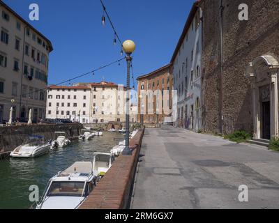 Werfen Sie einen Blick auf ein typisches Livorno-Viertel in der Toskana mit Wasserstraßen im venezianischen Stil und kleinen Motorbooten entlang der Seiten, Italien. Stockfoto