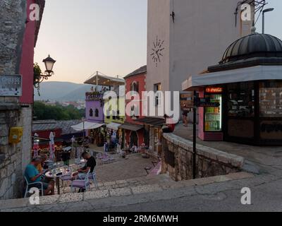 Menschen vor einem Café in der farbenfrohen Altstadt von Mostar und UNESCO-Stätte an einem Sommerabend. Bosnien und Herzegowina, 26. August 2023. Stockfoto