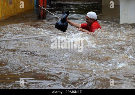 (140121) -- JAKARTA, 21. Januar 2014 (Xinhua) -- Ein Mann hält Ein Seil, um in Kampung Melayu in Jakarta, Indonesien, am 21. Januar 2013 durch Hochwasser zu waten. Die durch starken Regen verursachte Überschwemmung hat acht Menschen getötet und mehr als 60.000 andere gezwungen, aus ihrem Haus in Jakarta zu fliehen, sagte der Beamte. (Xinhua/Veri Sanovri)(zhf) INDONESIA-JAKARTA-FLOOD PUBLICATIONxNOTxINxCHN JAKARTA 21. Januar 2014 XINHUA ein Mann hält ein Seil zum Kalb durch Hochwasser in Kampung nacktesPerson Melayu in Jakarta Indonesien 21. Januar 2013 durch schweren Regen VERURSACHTE Überschwemmung hat acht Prominente GETÖTET und mehr als 60 000 andere gezwungen zu fliehen Stockfoto