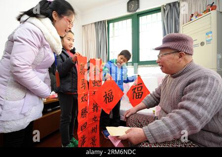 (140122) -- HANGZHOU, Jan. 22, 2014 (Xinhua) -- Pan Xiaoyan (2nd L), an 8-year old girl, and Chen Duanji (2nd R), an 8-year old boy, send Chinese couplets written by themselves to an old man Li Youlin, as gifts to greet the upcoming Spring Festival, in Hangzhou City, capital of east China s Zhejiang Province, Jan. 22, 2014. Chinese have the tradition to fix the couplet, which are red scrolls with rhyming phrases, on their doors during the Spring Festival, hoping it can bring in good luck. The Spring Festival falls on Jan. 31 this year. (Xinhua/Ju Huanzong) (ry) CHINA-HANGZHOU-SPRING FESTIVAL-C Stock Photo