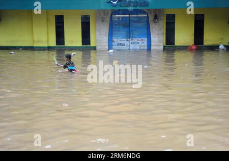 (140122) -- JAKART, Jan. 22, 2014 (Xinhua) -- A girl wades through floodwater in Jakarta, Indonesia, Jan. 22, 2014. In the Indonesian capital of Jakarta, some of the displaced people have started returning homes to clean their houses as the flood recedes, but they are still reluctant to return at night, according to officials. (Xinhua/Zulkarnain) (zjl) INDONESIA-JAKARTA-FLOOD PUBLICATIONxNOTxINxCHN   Jan 22 2014 XINHUA a Girl Wade Through flood water in Jakarta Indonesia Jan 22 2014 in The Indonesian Capital of Jakarta Some of The Displaced Celebrities have started Returning Homes to Clean the Stock Photo