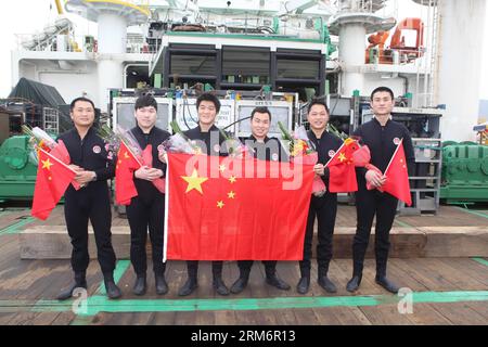 SIC-Taucher posieren für ein Gruppenfoto, nachdem sie sicher aus einer lebenden Kammer auf einem Schiff, das an einem Dock in Shenzhen, der südchinesischen Provinz Guangdong, ankert, am 25. Januar 2014 herausgekommen sind. Eine Tauchglocke brachte die Taucher am 12. Januar in eine Tiefe von 313,5 Metern unter das Südchinesische Meer. Dann kehrten die Taucher aus tiefem Wasser in die lebende Kammer auf ihrem Schiff zurück. Nachdem sie 380 Stunden in der Kammer geblieben waren, um das Inertgas in ihrer Gewebeflüssigkeit wieder auf normalen Druck zu bringen, kamen alle sechs Taucher am 25. Januar mit gesunden Körperbedingungen heraus. Dies stellte einen erfolgreichen Abschluss für Chinas erste 300-Meter-Sättigungsdiv dar Stockfoto