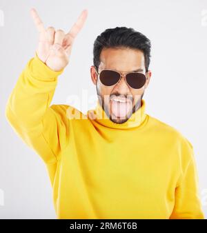 Mann, Hörner und Hand mit Sonnenbrille, Studioporträt und Rocksymbol für Geste, Kleidung und weißen Hintergrund. Junge, Model und Teufelsfinger für Stockfoto