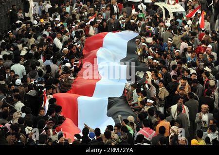 (140211) -- SANAA, 11. Februar 2014 (Xinhua) -- jemenitische Menschen halten eine riesige Nationalflagge des Jemen aufrecht, während sie an einem Festakt in Sanaa, Jemen, am 11. Februar 2014 teilnehmen. Zehntausende von jemenitischen Menschen nahmen an der Veranstaltung zum Gedenken an den dritten Jahrestag der Revolution von 2011 Teil, die den ehemaligen Präsidenten Ali Abdullah Saleh zum Rücktritt zwang. (Xinhua/Mohammed Mohammed) JEMEN-SANAA-REVOLUTION-JAHRESTAG-FEIER PUBLICATIONxNOTxINxCHN SANAA 11. Februar 2014 XINHUA JEMEN-Prominente halten eine riesige Nationalflagge des JEMEN aufrecht, während sie an einer Feier in Sanaa Jemen AM 11. Februar teilnehmen Stockfoto