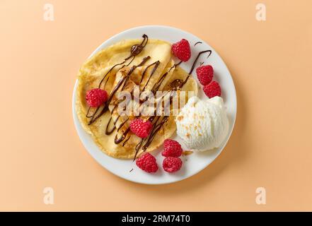 Frisch gebackener Crepe mit Himbeeren und Eis auf weißem Teller, Blick von oben Stockfoto