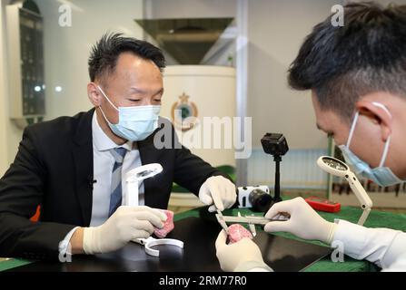 Hongkong, China. August 2023. Lau Yuk-Lung (L), ein Vorgesetzter im Geheimdienstbüro des Hong Kong Customs, untersucht die Textur eines Stückes Jade mit seinem Kollegen in Hongkong, Südchina, 18. August 2023. ZU „Feature: Meet HK Customs“, dem ersten Identifizierungsteam für kulturelle Relikte von nat'l. Credit: Li Gang/Xinhua/Alamy Live News Stockfoto