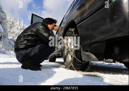 (140218) -- WUHAN, 18. Februar 2014 (Xinhua) -- Ein Fahrer installiert Reifenketten an seinem Auto auf einer mit Eis und Schnee bedeckten Straße in der zentralchinesischen Provinz Hubei, 18. Februar 2014. Viele Teile von Hubei waren von Montag Abend bis Dienstag Zeuge von starkem Schnee, der den Verkehr und die Ernten verheerend beeinträchtigt. (Xinhua/Hao Tongqian)(wjq) CHINA-HUBEI-SNOWFALL (CN) PUBLICATIONxNOTxINxCHN Wuhan 18. Februar 2014 XINHUA A Fahrer installiert Reifenketten an sein Auto AUF einer mit EIS und Schnee bedeckten Straße in Zentralchina Provinz S Hubei 18. Februar 2014 VIELE Teile von Hubei waren Zeuge von schwerem Schnee von Montag Abend bis Dienstag, der HAV verursacht Stockfoto