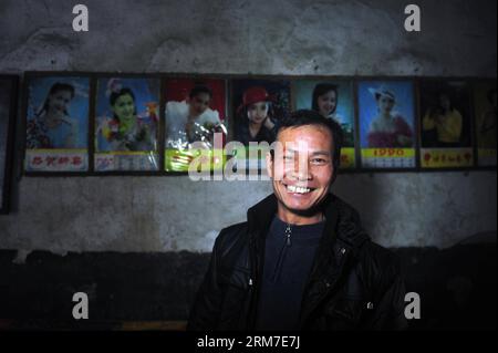 (140228) -- RONG AN, 22. Februar 2014 (Xinhua) -- Villager Mo Shihe wird in seinem Haus mit alten Plakaten an der Wand im Dorf Tongban, Kreis Rong an, südchinesische autonome Region Guangxi Zhuang, 22. Februar 2014 gesehen. Der sechsundvierzigjährige Long Gexiong wurde im Dorf Tongban geboren, einem kleinen Dorf weit entfernt in den Berggebieten der autonomen Region Guangxi Zhuang. Vor etwa zwanzig Jahren verließ lange Zeit die Heimatstadt, um zu arbeiten, wie viele seiner Generationen es beschlossen, und ließ seinen Vater allein zu Hause. Als immer mehr junge Menschen aus der Heimatstadt zogen, lag das einst lebendige Dorf auf dem d Stockfoto