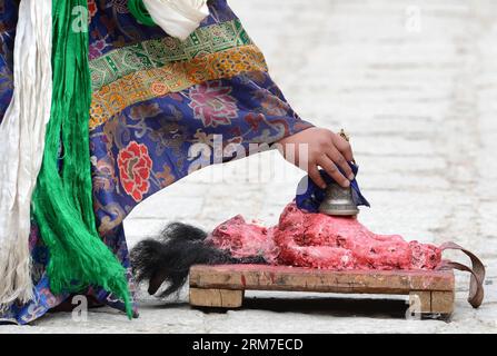 (140228) -- LHASA, 28. Februar 2014 (Xinhua) -- ein tibetischer buddhistischer Mönch zähmt einen mimischen bösen Geist, der aus Tsampa, einem Gerstenmehlfutter, hergestellt wird, während eines Cham-Tanzrituals, das anlässlich des bevorstehenden Losars im Kloster Tsurphu im Doilungdeqen County von Lhasa, der Hauptstadt der autonomen Region Tibet im Südwesten Chinas, am 28. Februar 2014 abgehalten wird. Der Cham-Tanz ist ein Ritual, das von tibetischen buddhistischen Mönchen durchgeführt wird, um böse Geister zu exorzieren. Die Tänzerinnen tragen Masken verschiedener Tiere und mythische Figuren, während sie zur Begleitung religiöser Musik auftreten. Im Tsurphu-Kloster, einem Hauptsitz der Kagyu-Schule in Stockfoto