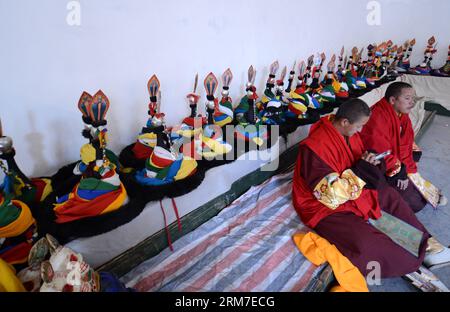 (140228) -- LHASA, Feb. 28, 2014 (Xinhua) -- Two Tibetan Buddhist monks take a rest during a Cham dance ritual held to celebrate the upcoming Losar at the Tsurphu Monastery in Doilungdeqen County of Lhasa, capital of southwest China s Tibet Autonomous Region, Feb. 28, 2014. The Cham dance is a ritual performed by Tibetan Buddhist monks to exorcise evil spirits. The dancers wear masks of various animals and mythical figures as they perform to the accompaniment of religious music. At the Tsurphu Monastery, a main base of the Kagyu school in Tibetan Buddhism, the Cham dance is usually performed t Stock Photo