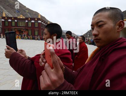 (140228) -- LHASA, 28. Februar 2014 (Xinhua) -- buddhistische Mönche machen Fotos eines Tanzrituals der Cham, das anlässlich des bevorstehenden Losars im Kloster Tsurphu im Doilungdeqen County von Lhasa, der Hauptstadt der autonomen Region Tibet im Südwesten Chinas, am 28. Februar 2014 abgehalten wird. Der Cham-Tanz ist ein Ritual, das von tibetischen buddhistischen Mönchen durchgeführt wird, um böse Geister zu exorzieren. Die Tänzerinnen tragen Masken verschiedener Tiere und mythische Figuren, während sie zur Begleitung religiöser Musik auftreten. Im Tsurphu-Kloster, einer Hauptbasis der Kagyu-Schule im tibetischen Buddhismus, wird der Cham-Tanz in der Regel zwei Tage vor dem Tanz aufgeführt Stockfoto