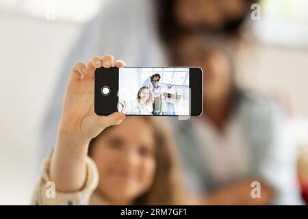 Lächelndes kaukasisches Teenie-Mädchen, Millennials-Frau und alte Großmutter machen Selfie auf dem Telefon-Bildschirm, genießen Sie Freizeit Stockfoto